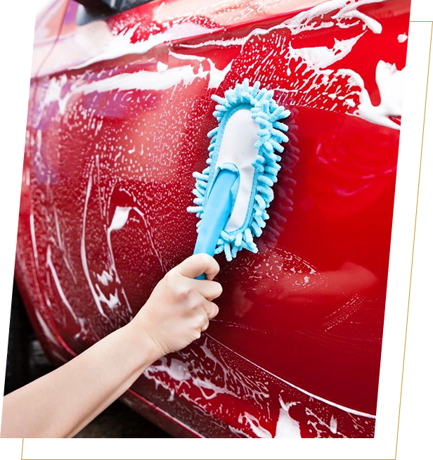 A person cleaning the side of a car with a brush.