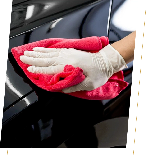 A person wiping down the hood of their car.