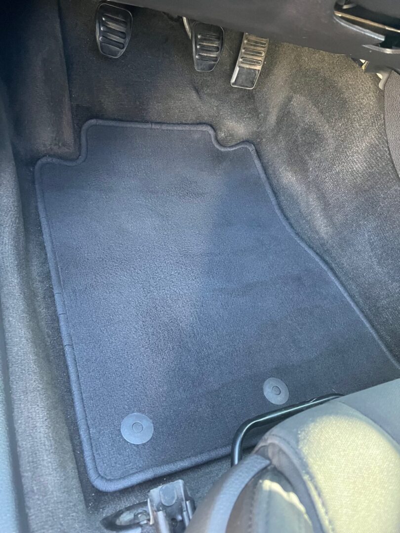 A car floor mat that is gray and has been cleaned.